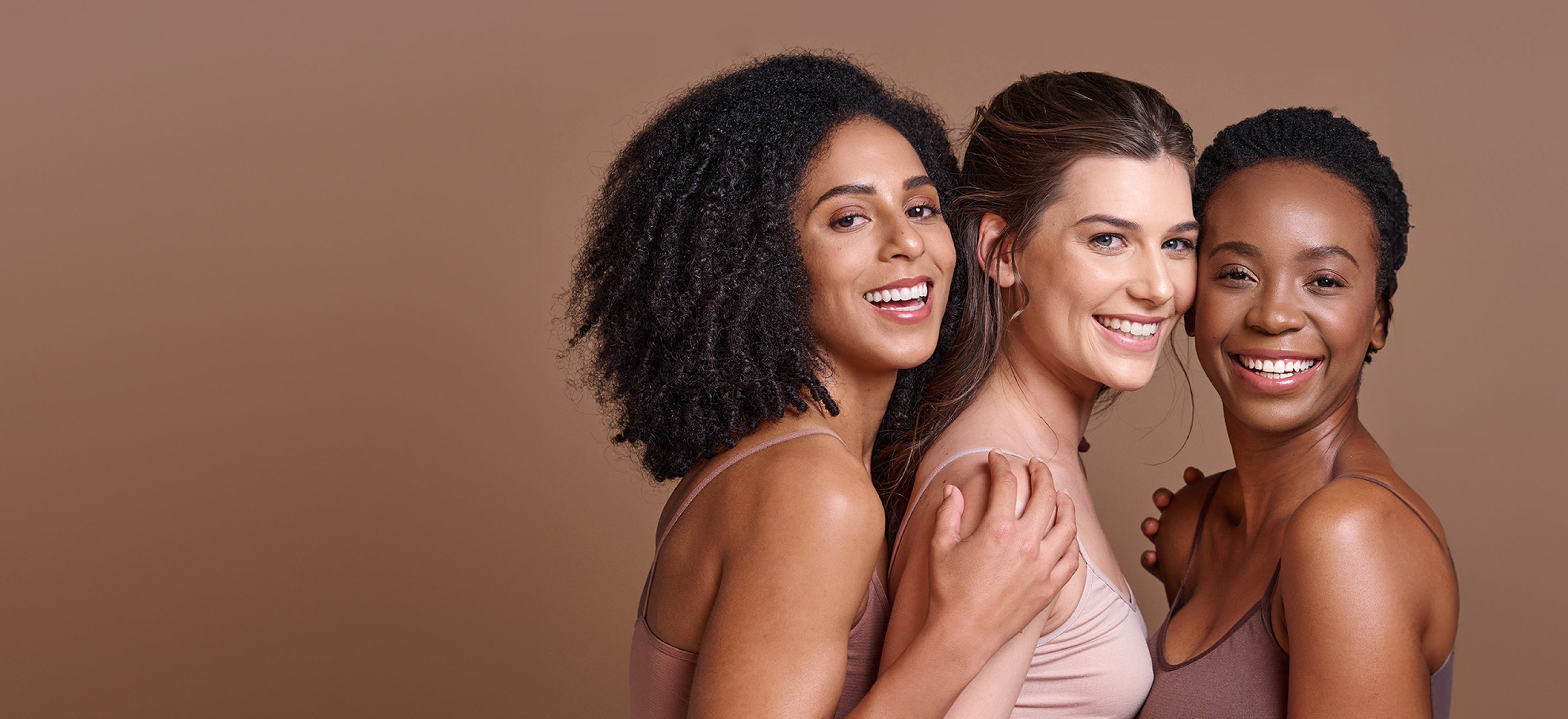 Three women looking directly ahead and smiling broadly