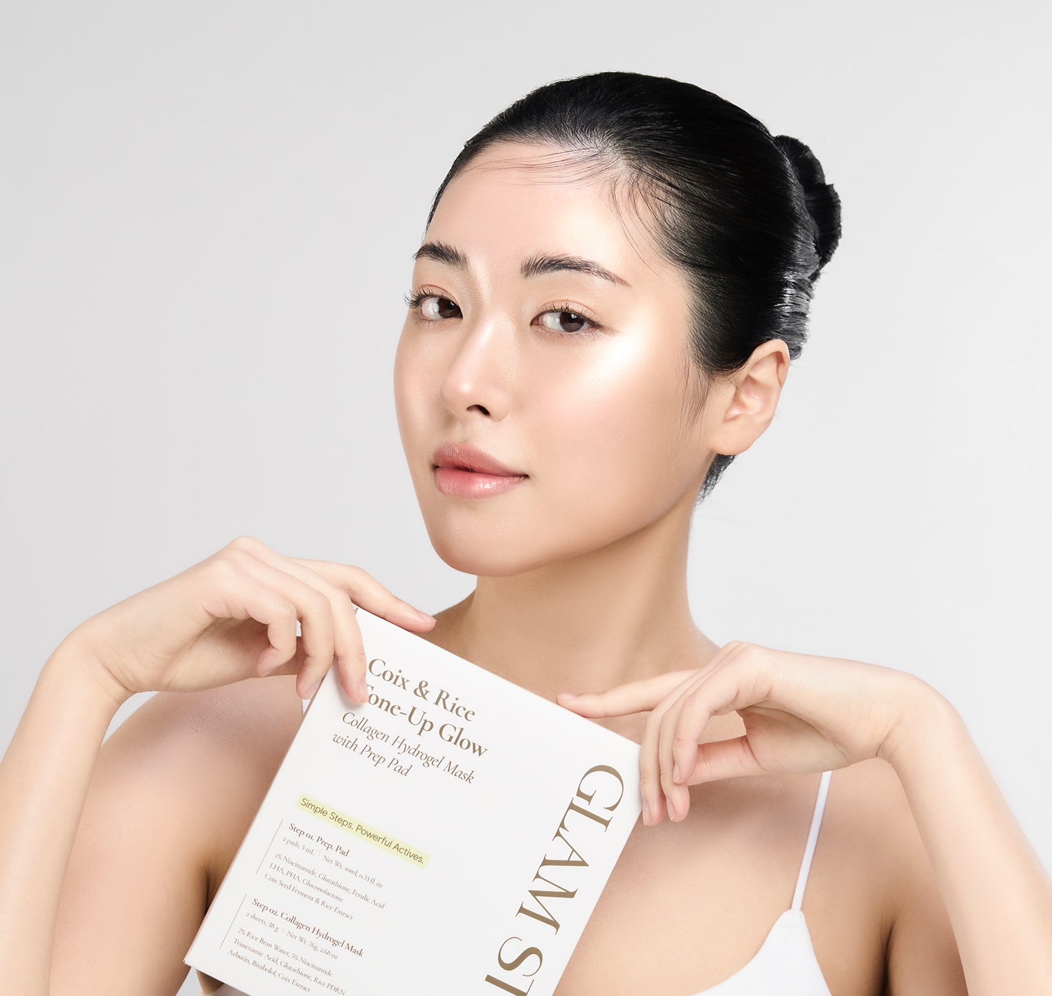 A model holding Coix & Rice Tone-Up Glow packaging and looking directly ahead