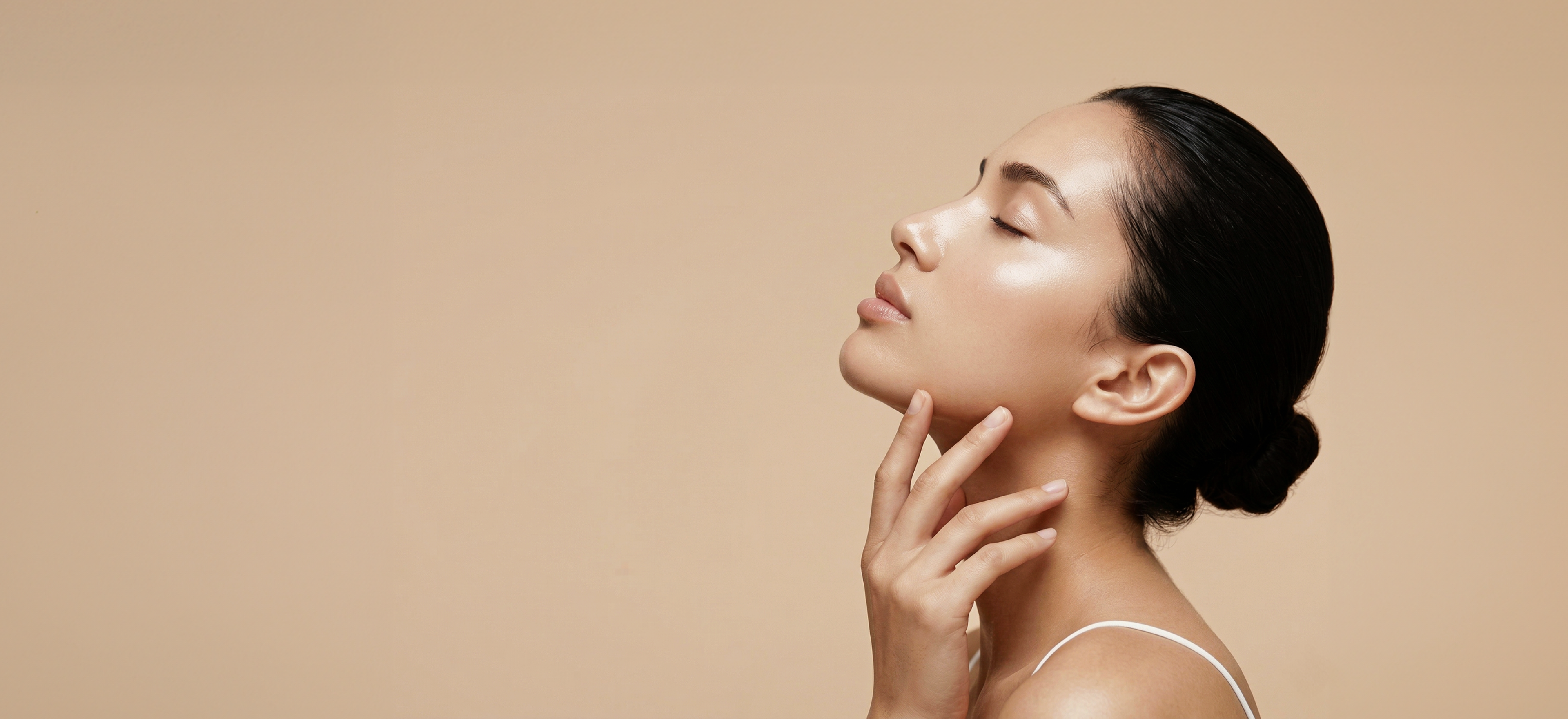 A side profile photograph of a female model tilting her head back at an angle with her eyes closed