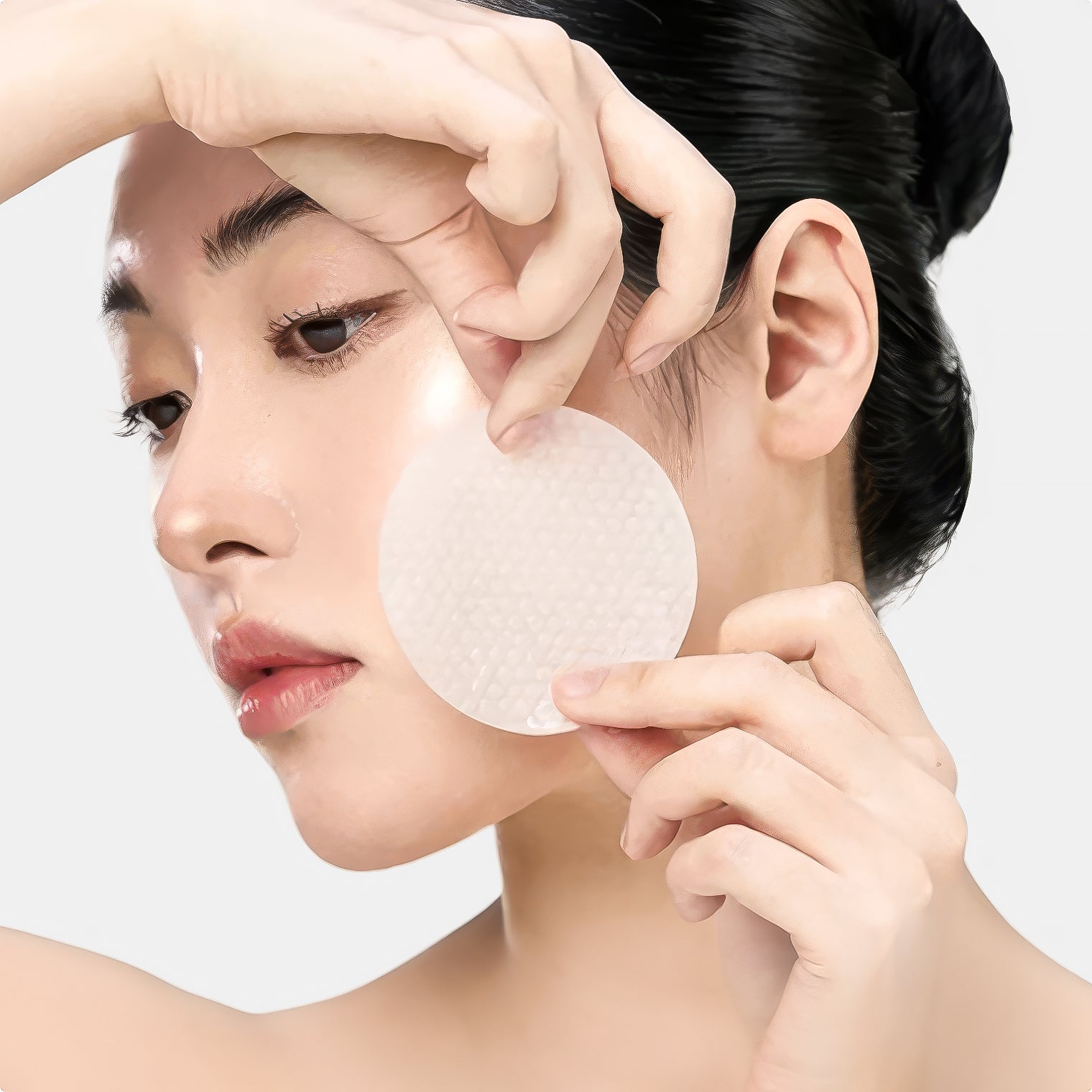 Close-up of a model applying a prep pad to the face