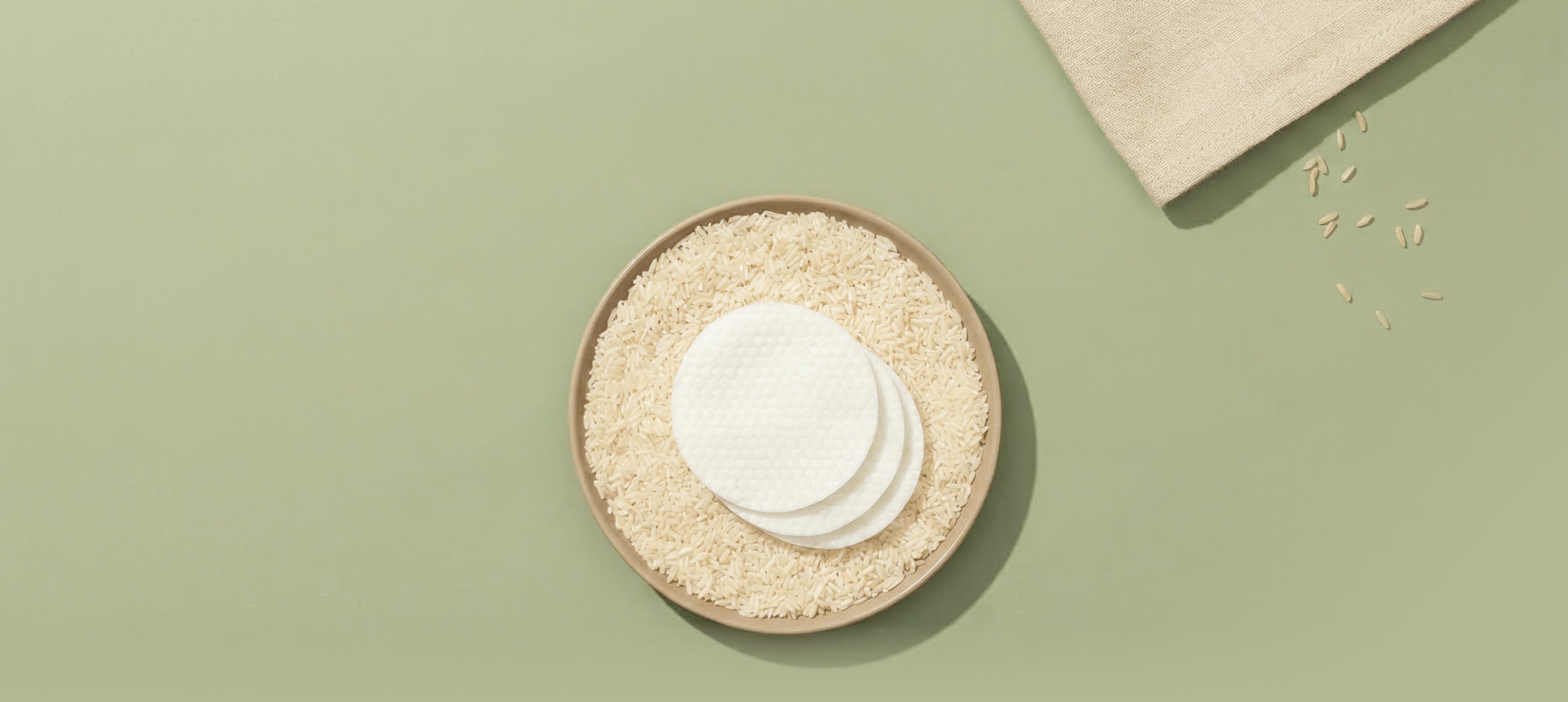 Round pads on a bowl of rice grains with a linen fabric accent