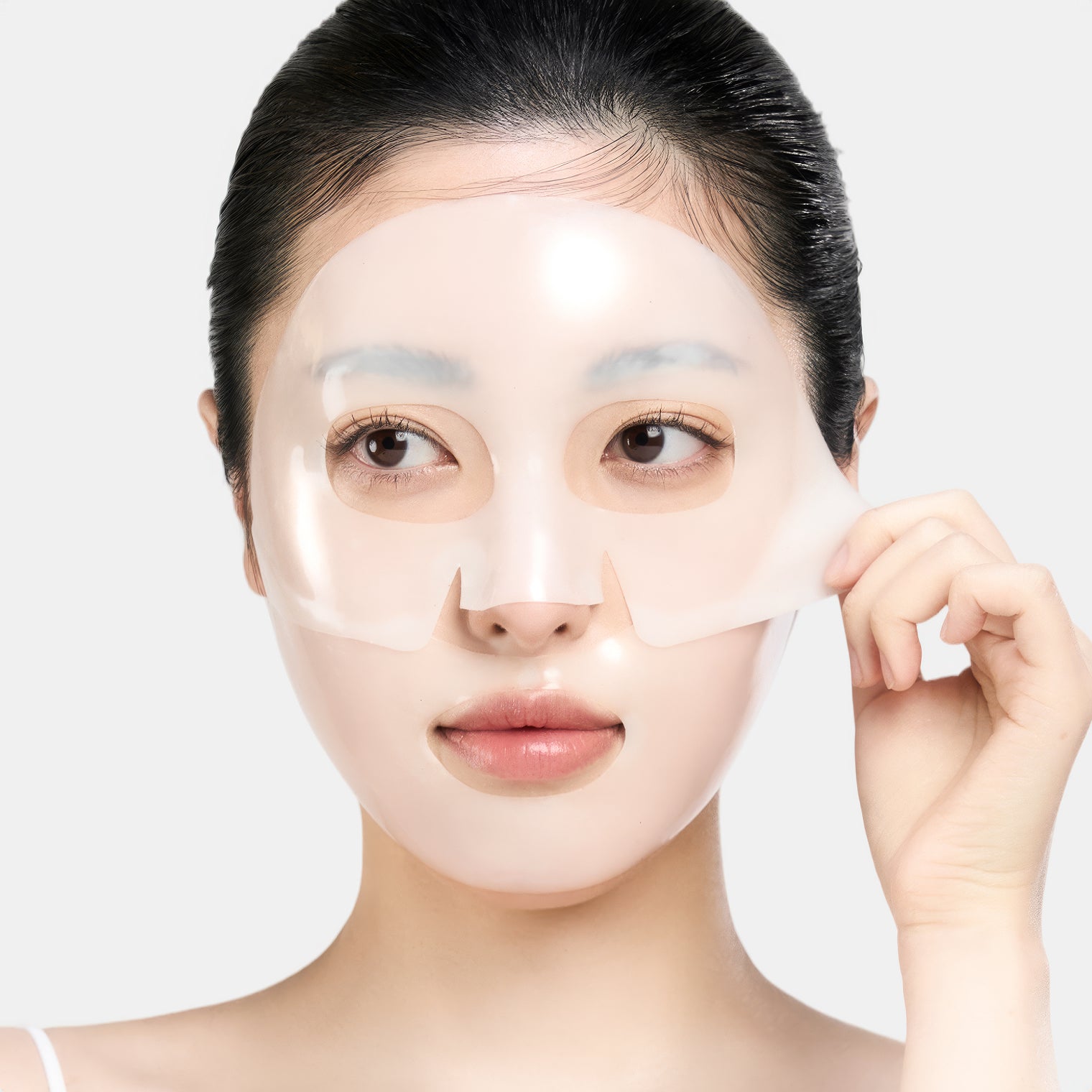 a model with a facial sheet mask applied, holding one edge