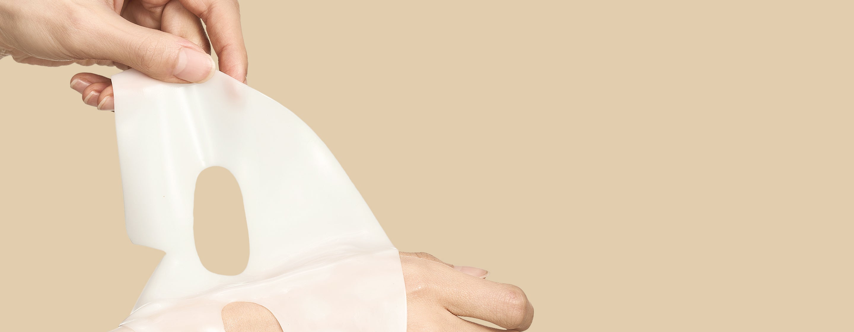 Close-up of a clear, hydrogel-like sheet mask on a hand