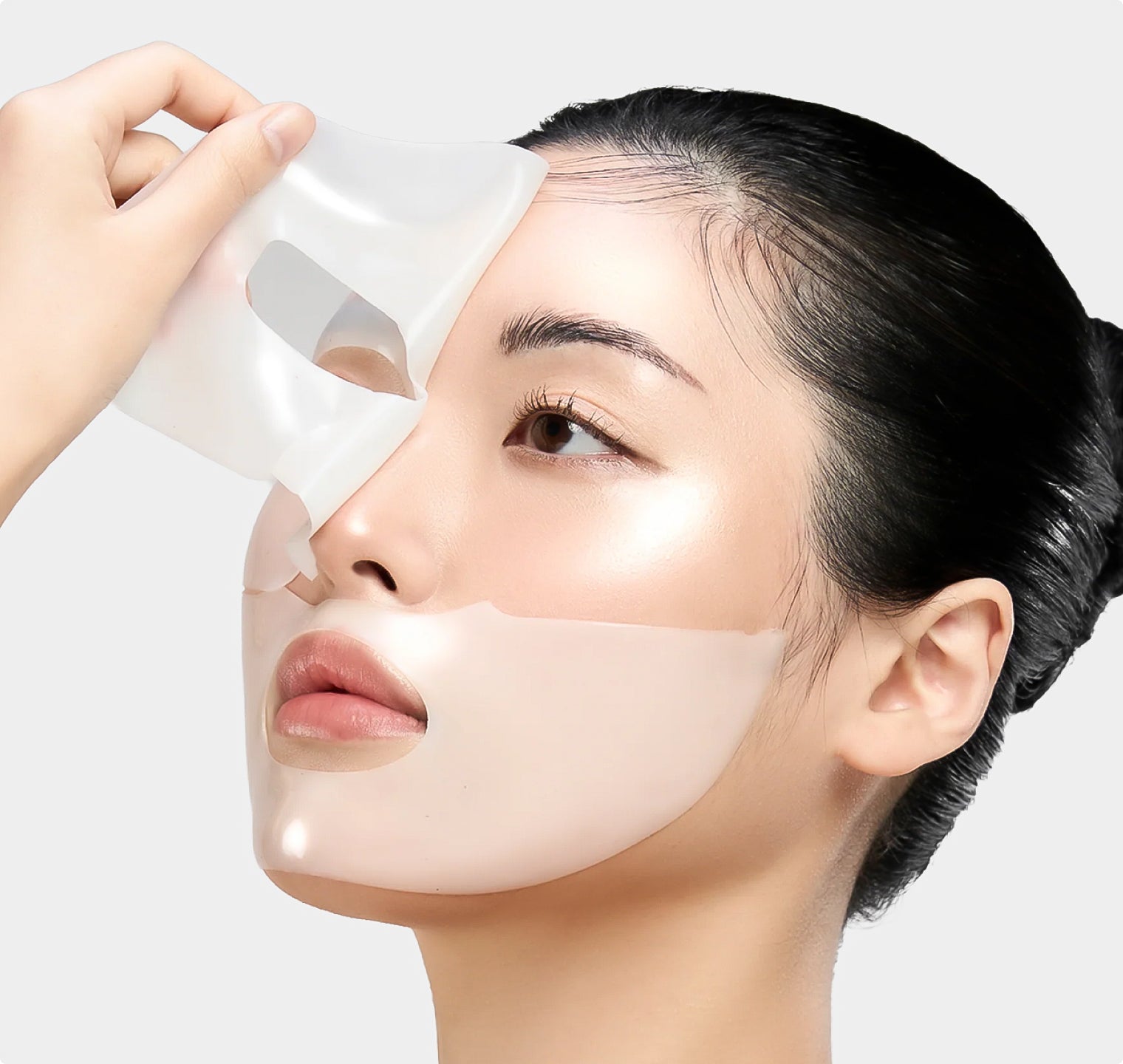 a model with a facial sheet mask applied, holding one edge